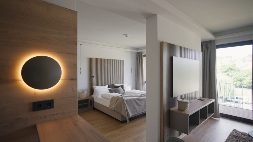 Hotelzimmer-Interior, Architekturfilm-Dreh, Imagefilm-Hotellerie, Immobilienvideo-Produktion, Weitwinkel-Aufnahme, Natürliches-Licht, Design-Holzlamellen, Balkonblick-Szene