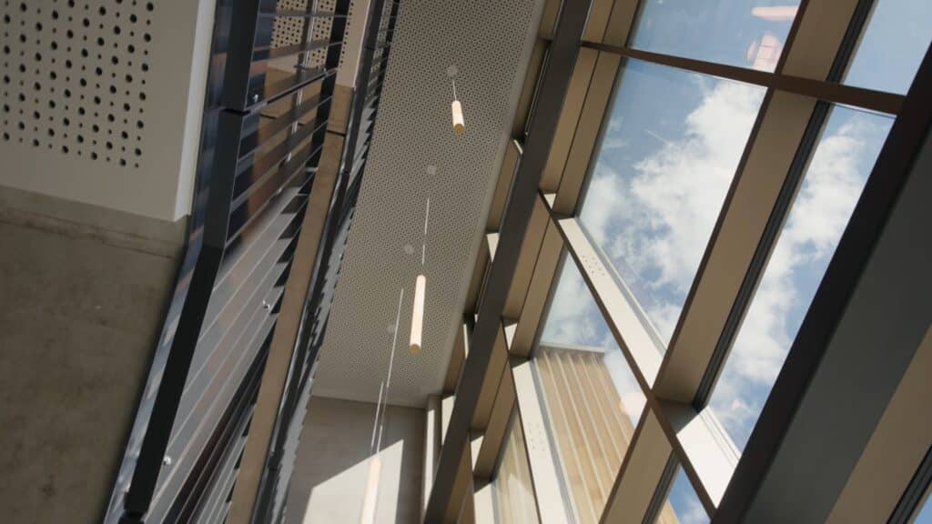 imagefilm-dreh, architektur-aufnahme, innenraum-glasfassade, modernes-atrium, glasdach-reflexionen, deckenleuchten-detail, aufwärts-perspektive, weitwinkel-perspektive, unternehmens-architektur, cinematischer-look