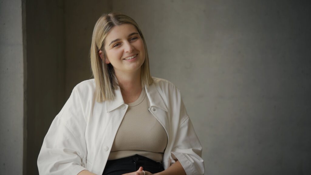 Interview-Setup Corporate-Interview Recruiting-Video Sitzendes-Statement Weiches-Licht Betonwand-Hintergrund Cinematic-Look Halbnahe-Einstellung Imagefilm-Dreh B2B-Content-Produktion