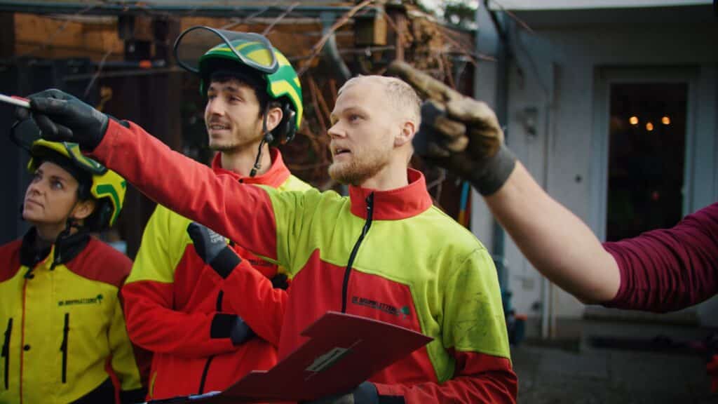 baumpflege-team-briefing, on-location-dreh, recruiting-video, imagefilm-dreh, sicherheitsausrüstung-helme, industrie-umgebung, einsatzplanung-klemmbrett, handwerk-outdoor, arbeitsalltag-dokumentation