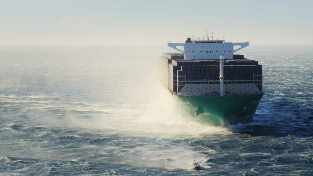 drohnenaufnahme-containerfrachter-auf-offener-see, maritime-logistik-seetransport, industrieumgebung-maritim, dynamische-wellen-und-gischt, b2b-imagefilm-szene, containerstapel-vorderansicht
