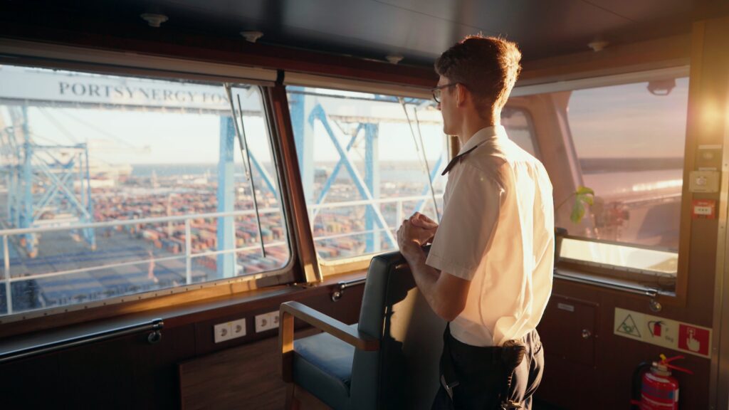 Schiffsbrücke-Perspektive, Containerhafen-Industrieumgebung, Containerterminal-Überblick, Hafenkran-Hintergrund, Maritime-Imagefilm-Szene, Seefahrt-Recruiting-Video, Steuerstand-Innenszene, Golden-Hour-Lichtstimmung, Arbeitsalltag-Visualisierung, B2B-Unternehmensfilm, Logistik-Branche, Cinematic-Look
