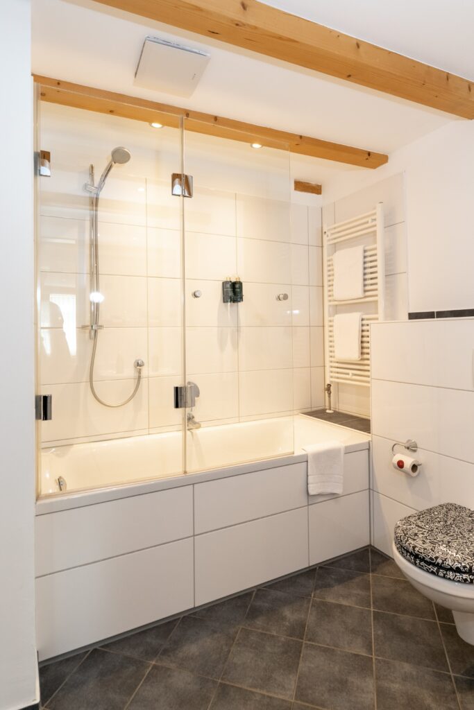 Interior-Aufnahme, Badezimmer-Szene, Architektur-Film, Immobilien-Video, Hotel-Video, Badewanne-Duschwand, Glas-Duschabtrennung, Handtuch-Heizkörper, Fliesen-Design, Sanitär-Produktvideo, Werbefilm-Location, Deckenspots-Beleuchtung, Set-Design