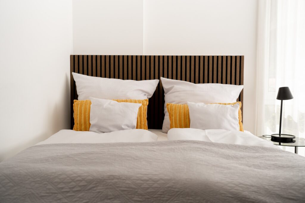Hotel-Imagefilm Interior-Setup Schlafzimmer-Szene Bett-Detail Holz-Headboard Weiß-Gelb-Farbkonzept Tageslicht-Setup Lifestyle-Produktvideo Hospitality-Werbefilm