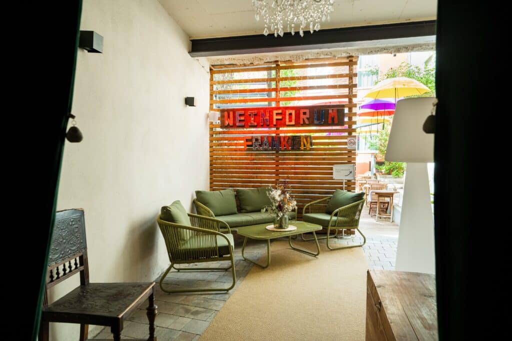 imagefilm-dreh gastro-location weinbar-terrasse lounge-bereich holzlamellen-hintergrund bunte-sonnenschirme available-light b-roll-aufnahme interieur-detail interview-setup-option
