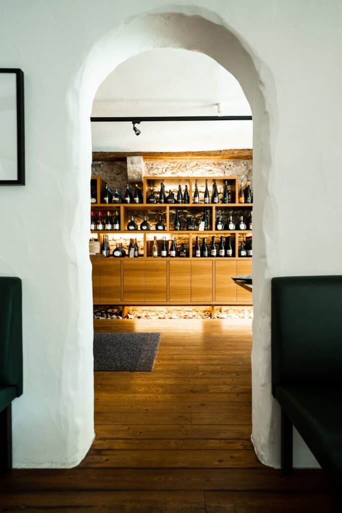 Imagefilm-Gastronomie, Restaurant-Interior, Weinregal-Hintergrund, Rundbogen-Durchgang, Warmlicht-Look, B-Roll-Aufnahme, Produktvideo-Wein, Location-Scouting