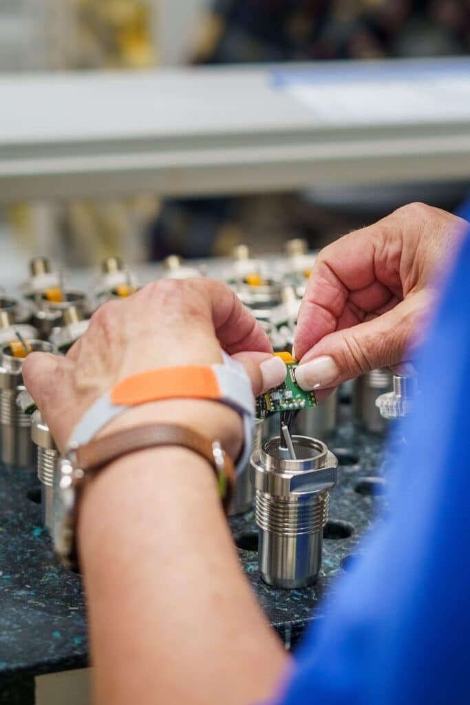 industrieumgebung-montage produktvideo-nahaufnahme elektronik-montage präzisionsarbeit-werkbank metallgehäuse-fertigung handmontage-produktion fertigungsprozess-detail b2b-industriefilm