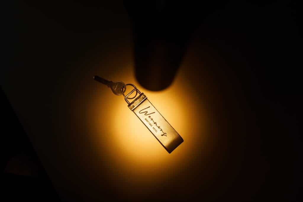 Produktvideo-Detailaufnahme Makro-Produktshot Low-Key-Lichtstimmung Warmlicht-Spot Hotel-Branding-Schlüsselanhänger Logo-Fokus Werbefilm-Requisite Cinematic-Look Close-up-Inszenierung