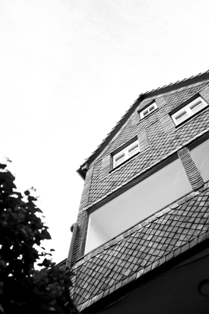 Architektur-Imagefilm, Gebäude-Fassade, Low-Angle-Aufnahme, Schindel-Fassade, Schwarzweiß-Look, Weitwinkel-Perspektive, Kamera-Setup-Outdoor
