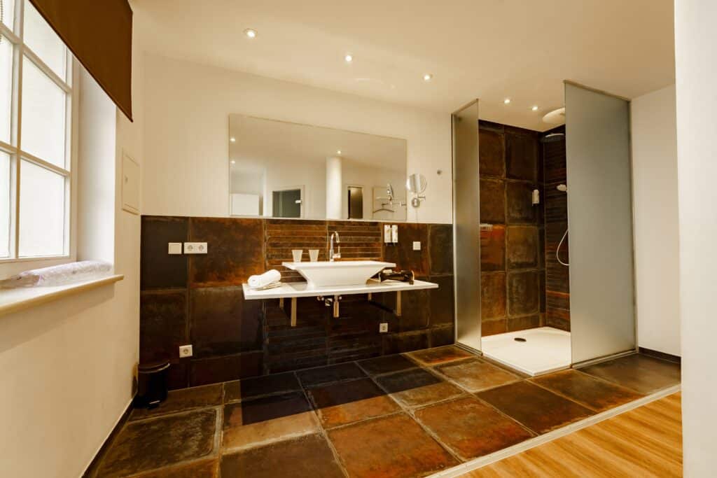 Architektur-Film, Immobilien-Video, Hotelbad-Interior, Walk-in-Dusche, Designfliesen-Detail, Spiegel-und-Waschtisch, Weitwinkel-Aufnahme, Produkt-Video-Sanitärtechnik, Objekt-Inszenierung, Saubere-Lichtsetzung