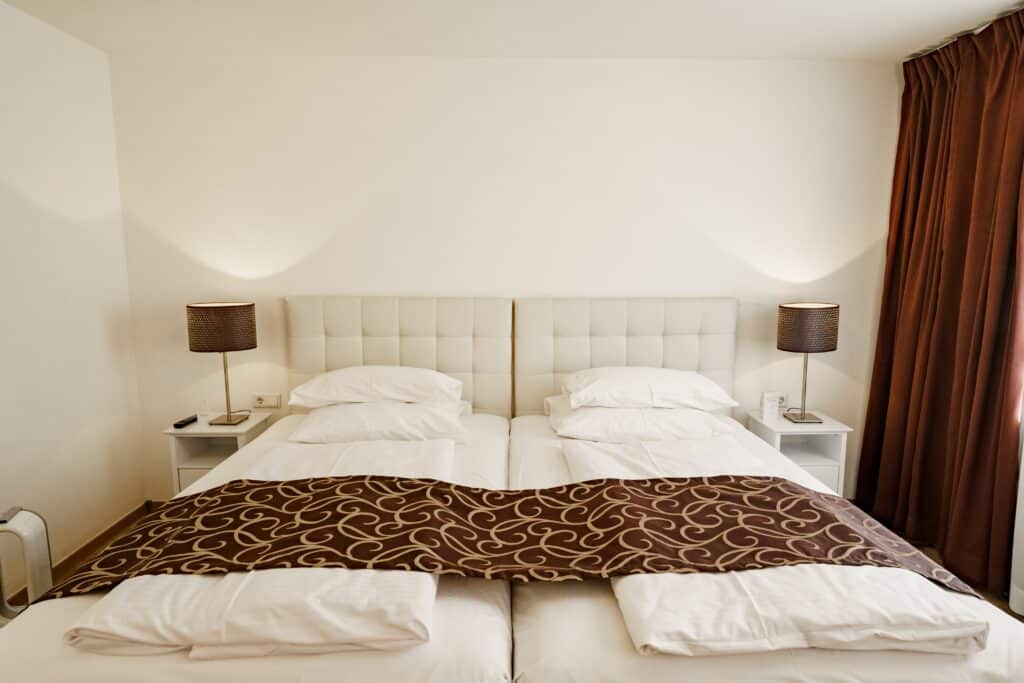 Hotelzimmer-Interior Imagefilm-Dreh-Hotellerie Symmetrische-Kameraperspektive Weiche-Lichtstimmung Weitwinkel-Aufnahme Set-Design-Bett-Nachttische Location-Scouting Werbefilm-Tourismus