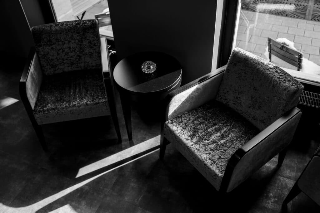 interview-setup lounge-bereich available-light schwarzweiß-look cinematisches-licht b-roll-szene corporate-location fenster-licht stuhl-tisch-arrangement mood-shot