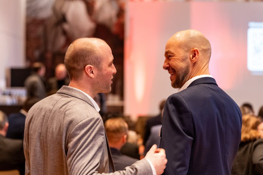 Messefilm-Produktion, Business-Event, Konferenz-Networking, Eventdokumentation, Corporate-Atmosphäre, Netzwerk-Gespräch, Bühne-im-Hintergrund