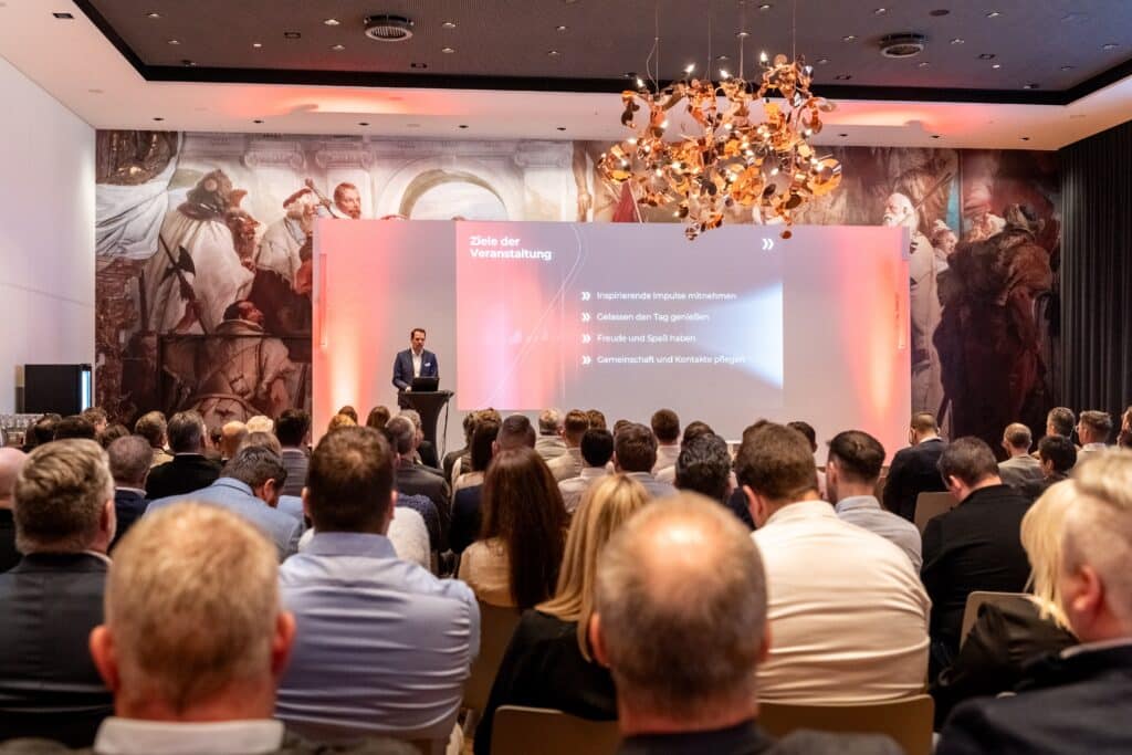 Eventfilm-Produktion, Konferenz-Aufzeichnung, Keynote-Bühne, Präsentations-Screen, Business-Publikum, Bühnen-Licht-Setup, Ton-Setup, Kamera-Setup, Unternehmens-Event, Live-Event-Dokumentation