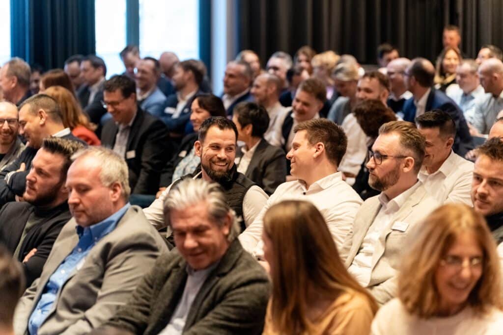 Eventfilm-Aufnahme, Business-Konferenz, B2B-Publikum, Networking-Moment, Messefilm-Szene, Unternehmens-Veranstaltung, Konferenz-Saal, Veranstaltungs-Dokumentation