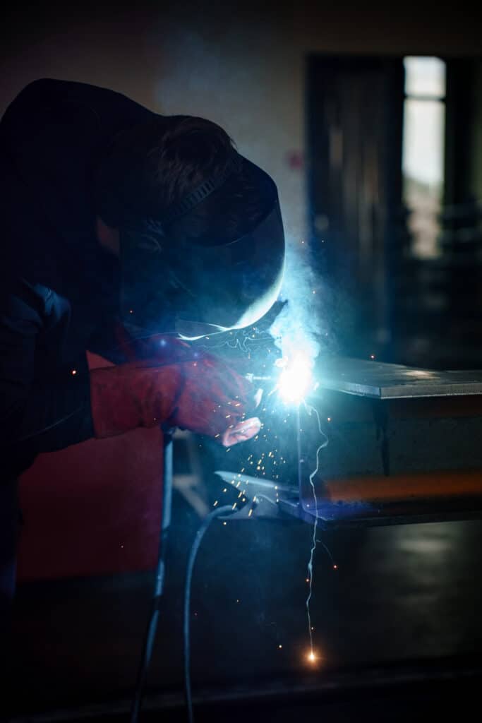 Industrieumgebung-Schweißarbeiten Funkenflug-Nahaufnahme Metallbau-Werkstatt Blaue-Lichtstimmung Schweißhelm-Schutzhandschuhe Produktionsprozess-Detail B2B-Produktvideo