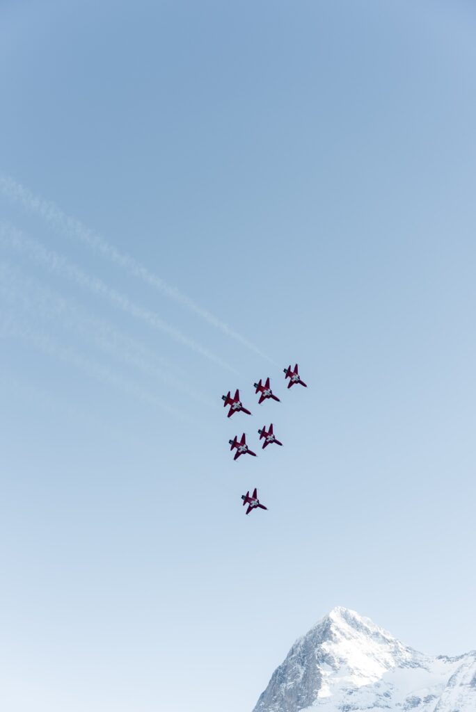 Eventfilm-Airshow, Kunstflug-Formation, rote-Jets, Alpen-Bergpanorama, Schnee-Gipfel, klarer-Himmel, Highspeed-Action, Outdoor-Dreh, Kinolook-Aufnahme