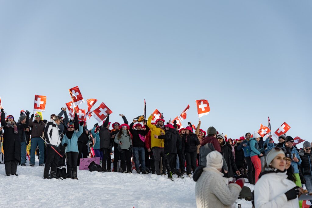 eventfilm-dreh winter-event schnee-landschaft menschenmenge schweizer-flaggen jubelnde-fans outdoor-produktion drohnenaufnahme sportveranstaltung b-roll-stimmung markenaktivierung