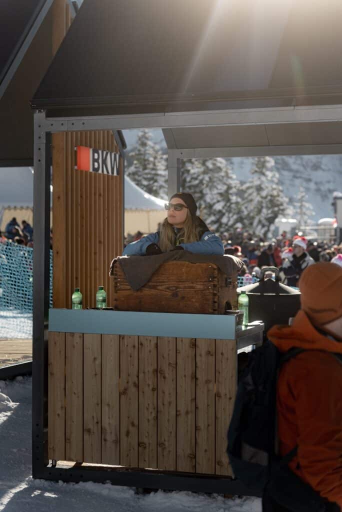 Eventfilm-Winter-Outdoor Markenstand-Holztheke Outdoor-Pavillon Schneelandschaft-Bergkulisse Besucher-Hintergrund Sonnenflare-Available-Light On-Location-Dreh Messefilm-Atmosphäre