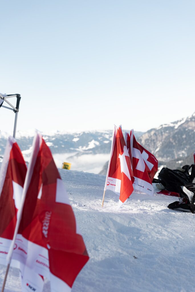 Outdoor-Imagefilm-Dreh Schneelandschaft Bergpanorama Schweizer-Flaggen Event-Branding On-Location-Setup Wintersport-Location Drohnenaufnahme-Option