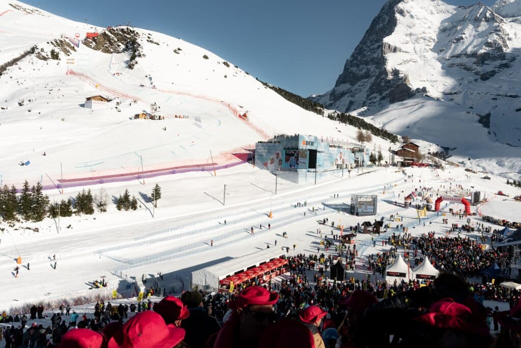 Eventfilm-Produktion Skirennen-Zielbereich Drohnenaufnahme-Wintersport Alpen-Bergkulisse Zuschauermenge-Sponsorenbranding Rennpiste-Absperrungen Live-Übertragung Outdoor-Kälte