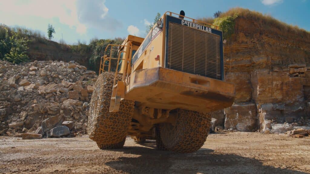 Industrieumgebung-Steinbruch Radlader-CAT-Baumaschine Low-Angle-Kameraperspektive Reifenketten-Detail Produktvideo-Baustelle Imagefilm-Industrie Erdbewegung-Schwerlast On-Location-Dreh-Felsabbau