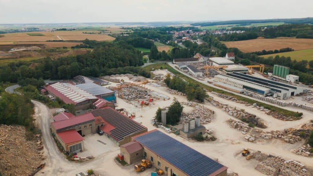 drohnenaufnahme-industrieanlage, steinverarbeitung-werksgelände, krananlagen-baumaschinen, naturstein-lagerflächen, solar-dach-hallen, imagefilm-industrie, b2b-videoproduktion