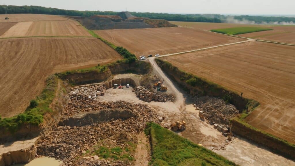 drohnenaufnahme-steinbruch industrieumgebung-tagebau baumaschinen-einsatz bagger-und-radlader schotterabbau-luftperspektive imagefilm-dreh industriefilm-b2b