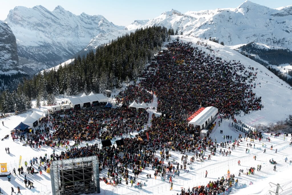 drohnen-aufnahme winter-berglandschaft alpen-panorama ski-event massen-publikum schnee-piste bühnen-zelte broadcast-technik kamera-turm eventfilm-produktion live-dokumentation