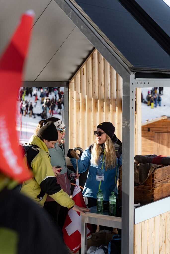 Eventfilm-Dreh, Wintersport-Event, On-Location-Dreh, Holz-Pavillon, Marken-Aktivierung, Besucher-Interaktion, Schweizer-Flagge, Getränkestand-Setup, Social-Media-Clip, natürliche-Lichtstimmung, authentische-B-Roll