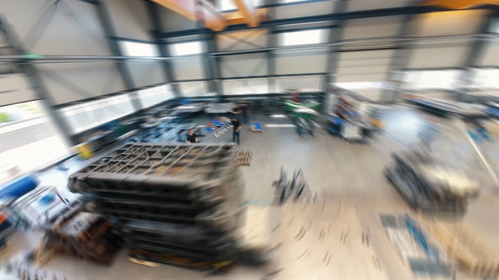 Industrieumgebung-Produktionshalle Drohnenaufnahme-Luftperspektive Dynamischer-Zoom-Effekt Weitwinkel-Bewegungsunschärfe Maschinenbau-Fertigung Imagefilm-B-Roll Werkstatt-Halle Krananlage-Overhead