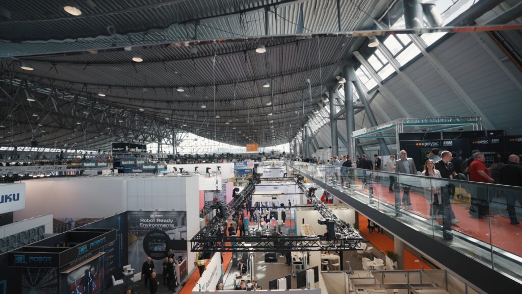 Technologie-Messe - Industrieumgebung - Messefilm-Aufnahme - Hallenübersicht - Weitwinkel-Perspektive - Aussteller-Stände - Robotik-Exponate - Besucherandrang - Event-Dokumentation - B2B-Content