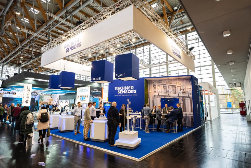 Messefilm-Aufnahme, moderner-Messestand, Industrieumgebung, Sensorsysteme-Produktpräsentation, B2B-Technologie-Exponate, Branding-Lichttraverse, Besucher-Interaktion, Live-Demo, Eventdokumentation, Corporate-Video