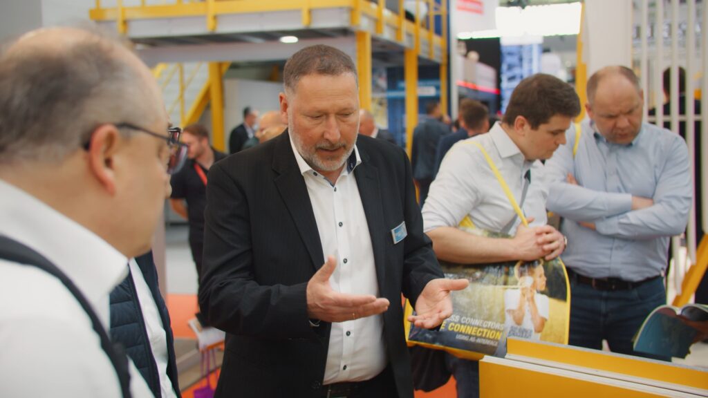 Messe-Film B2B-Messe Produkt-Demo Kunden-Gespräch Messe-Stand Industrie-Umgebung Nah-Aufnahme Hands-on-Erklärung Event-Dokumentation