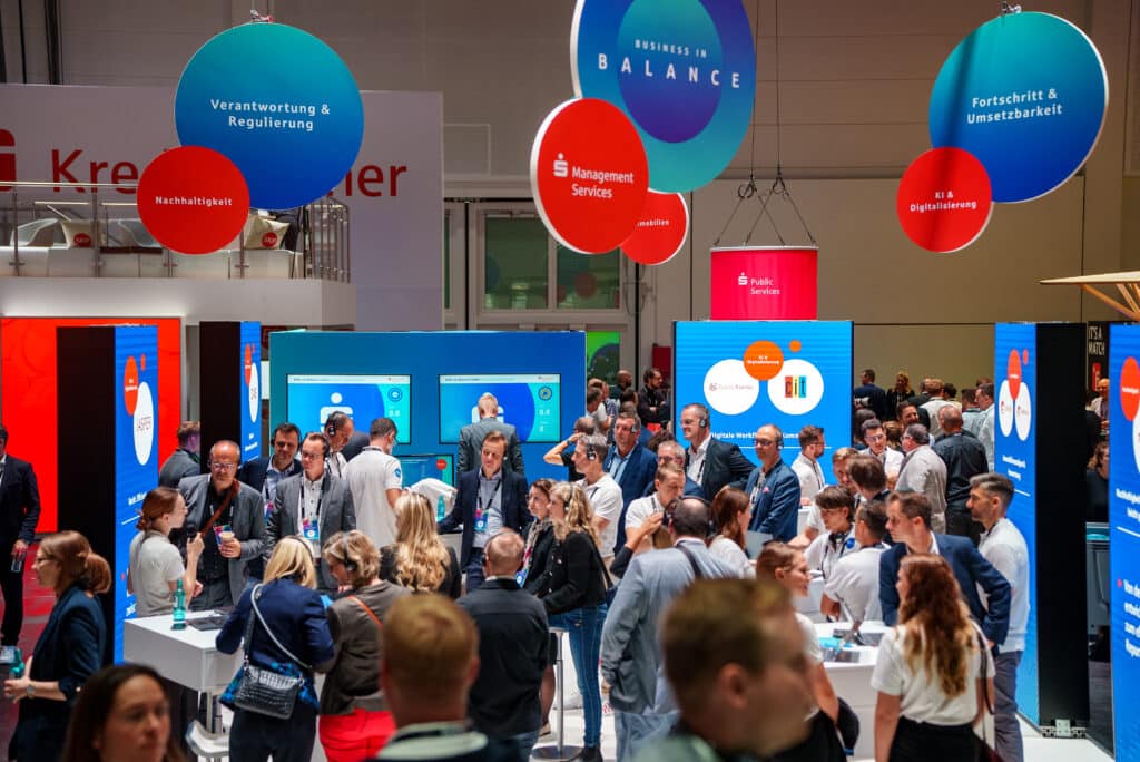 Messefilm-Produktion, B2B-Messe, Messestand-Branding, Produktdemo-Stationen, Besucher-Andrang, Digital-Displays, Corporate-Kommunikation, Networking-Szene, Eventdokumentation-Dreh, Live-Atmosphäre