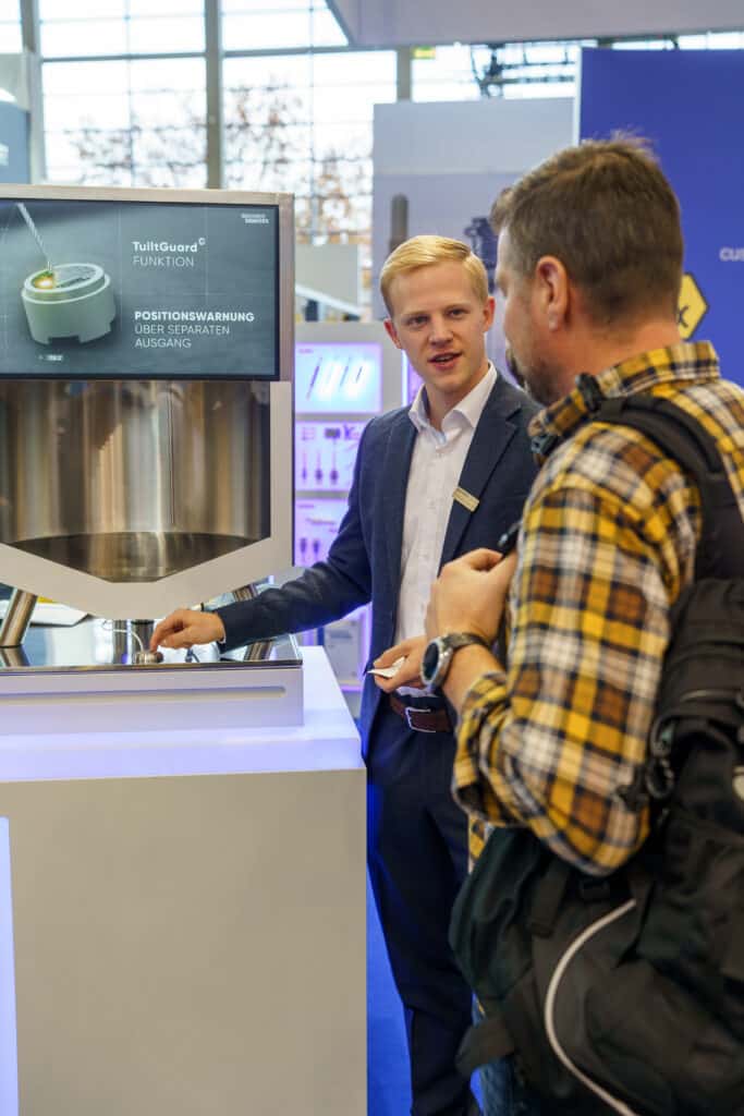 Messefilm-Produktdemo Industrie-Sensorik Messe-Standpräsentation Kunden-Beratung Display-Visualisierung Technik-Erklärung B2B-Kommunikation Detail-Nahaufnahme Touch-Bedienung
