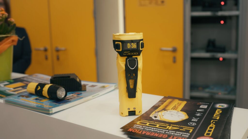 Produktvideo-Detailaufnahme Industrie-Taschenlampe-Produktshot Messestand-Setup Werbematerial-Flyer Close-up-Kameraperspektive Gelb-Corporate-Branding Prospekt-Auslage